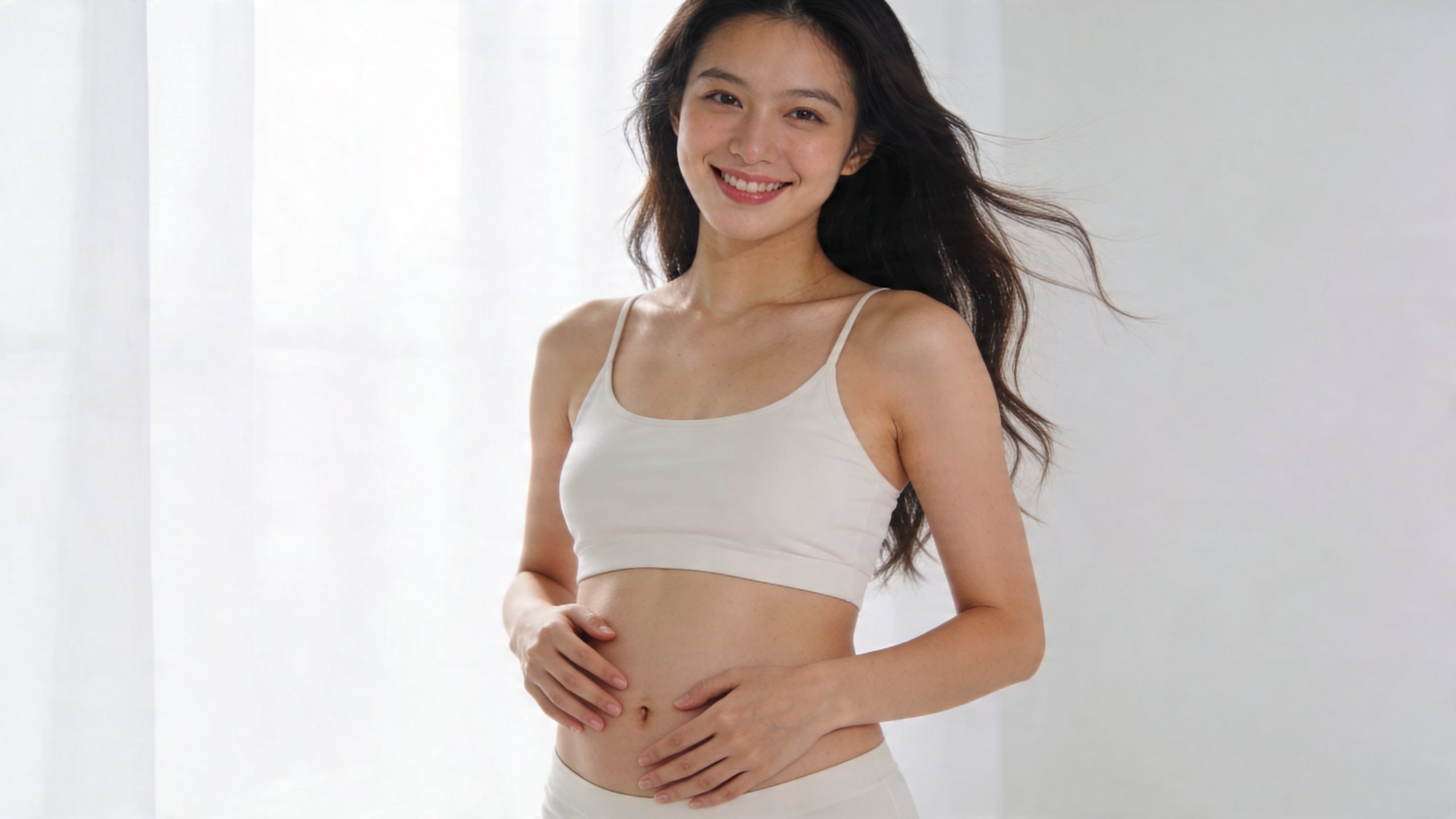 Une jeune femme souriante avec un ventre plat posant pour illustrer les bienfaits du drainage lymphatique abdominal.
