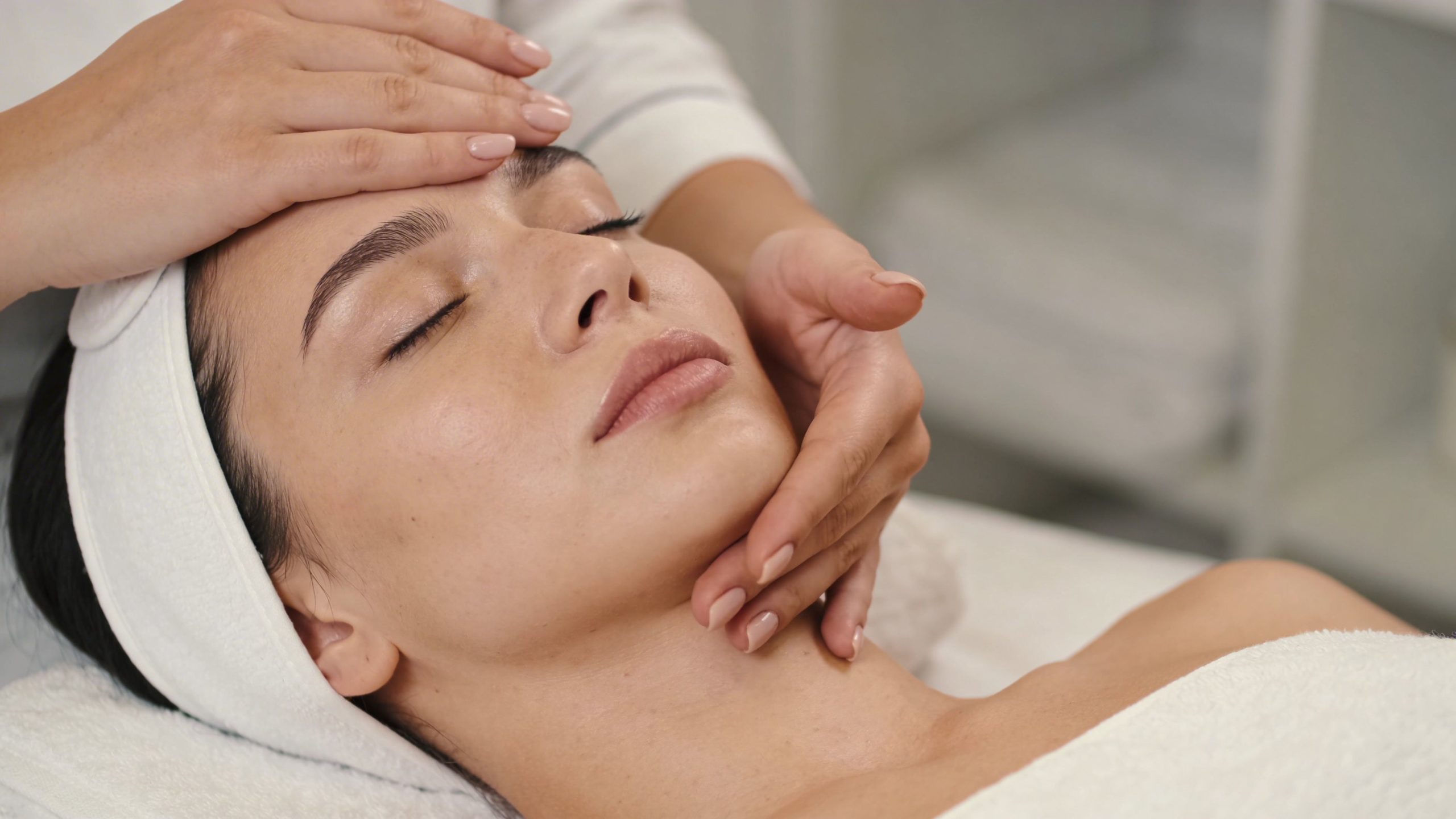 Une femme recevant un massage du visage relaxant et professionnel dans un salon de beauté spa luxueux.