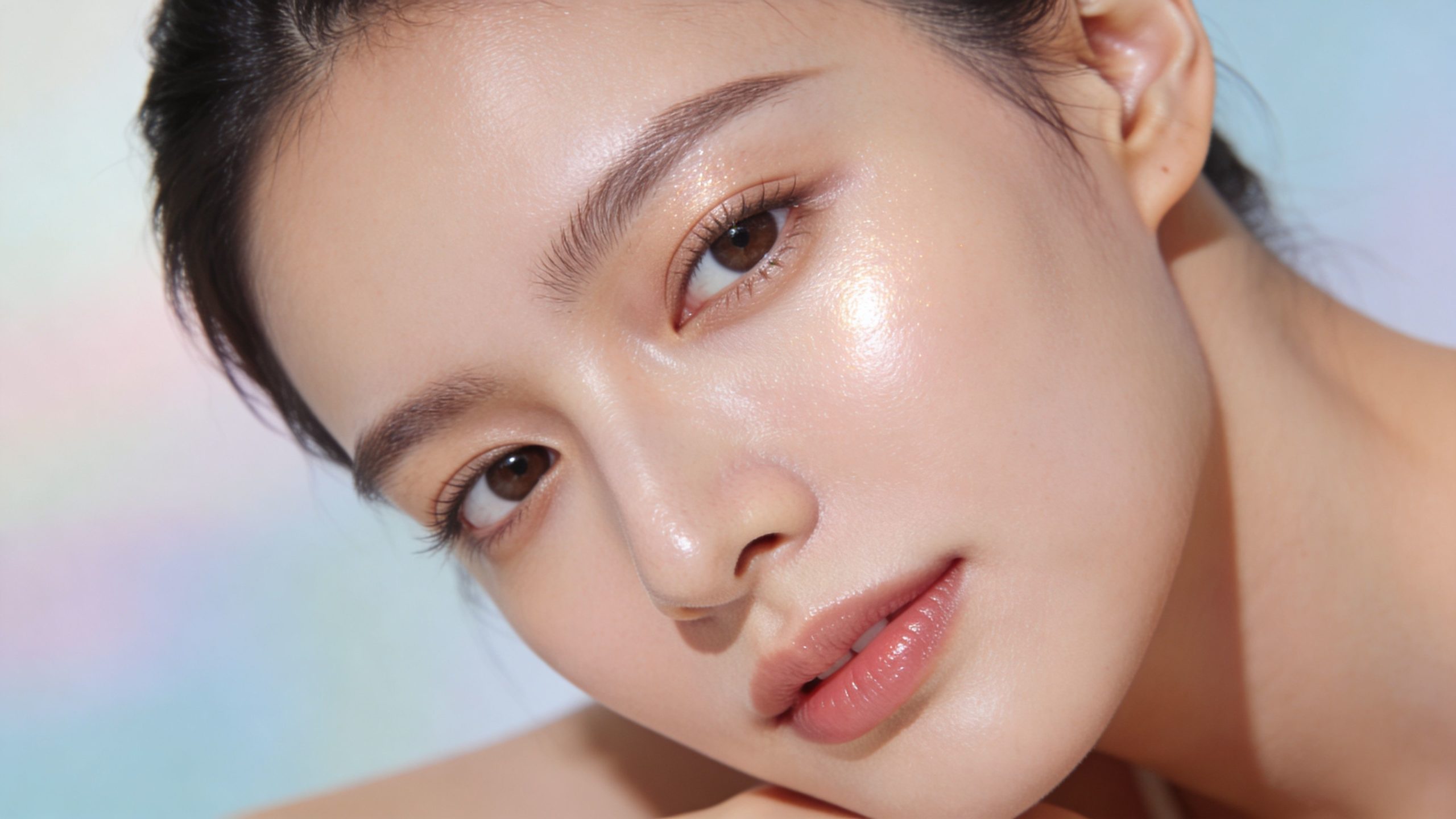 Gros plan sur le visage d'une femme à la peau éclatante et hydratée avec un maquillage naturel.