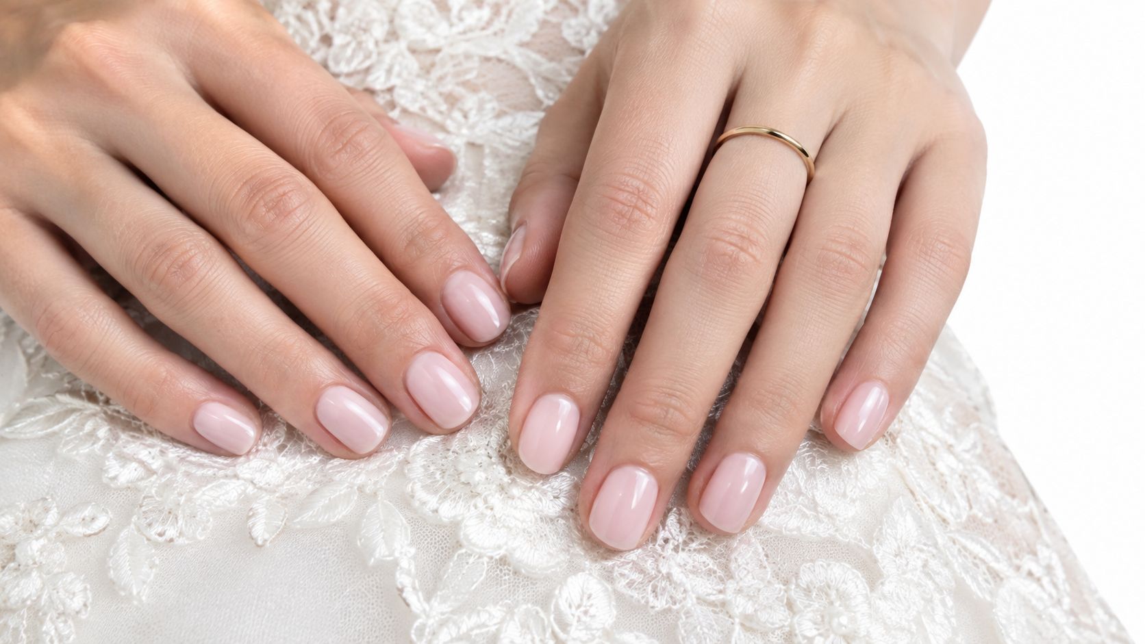 Gros plan sur les mains d'une mariée avec une manucure élégante et un anneau en or délicat.